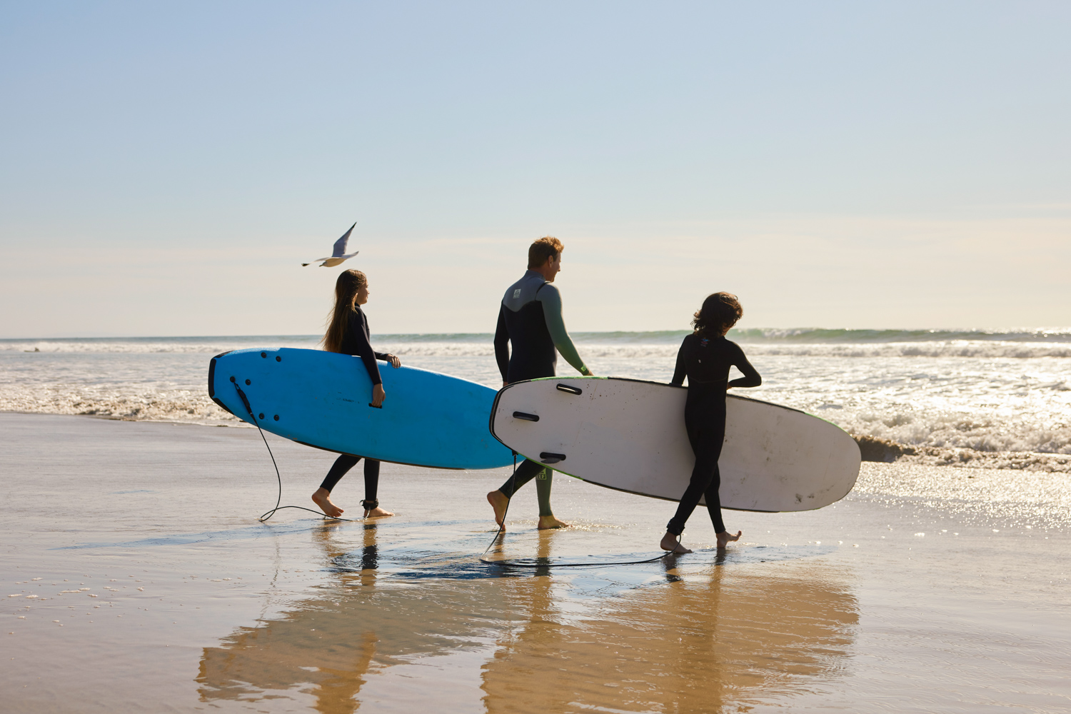family surf boards walking sand sky
