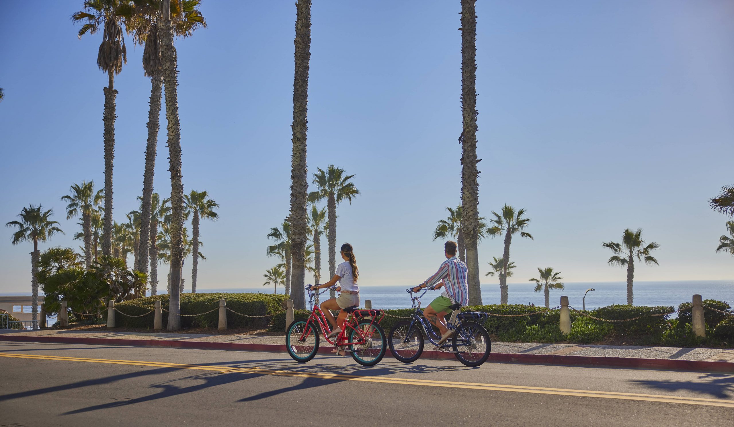 Couple riding a bike surrounded by palm trees in Oceanside