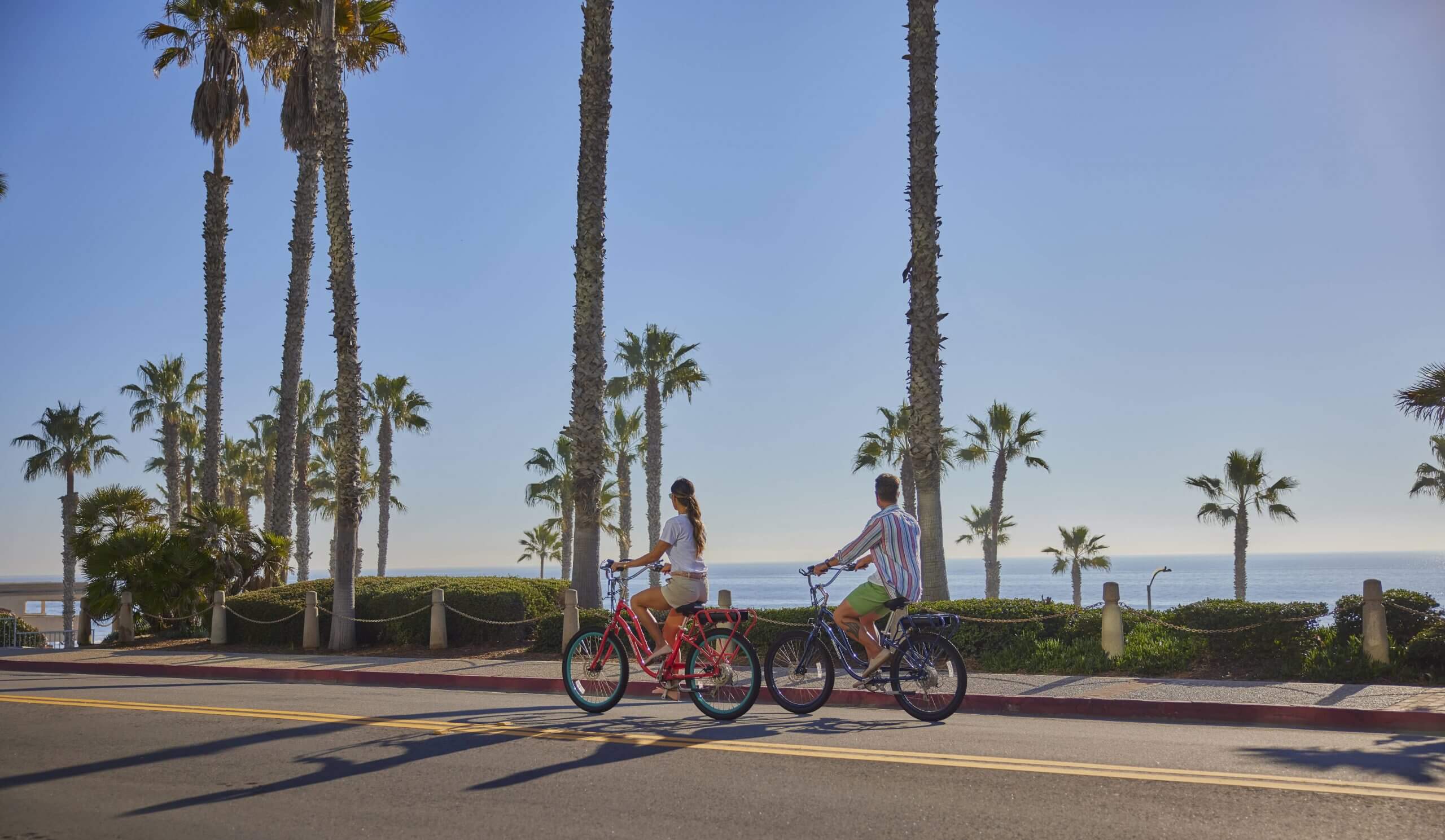 A couple riding a bike infront of the beach