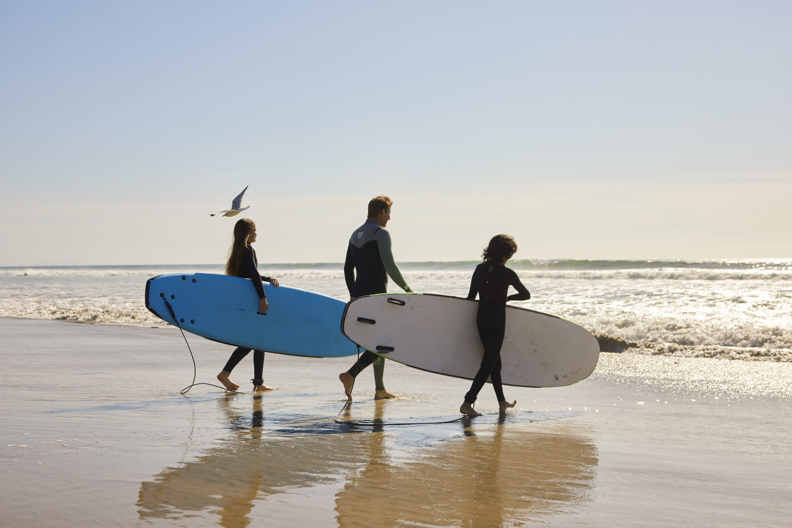 Three surfers walking out to the beach