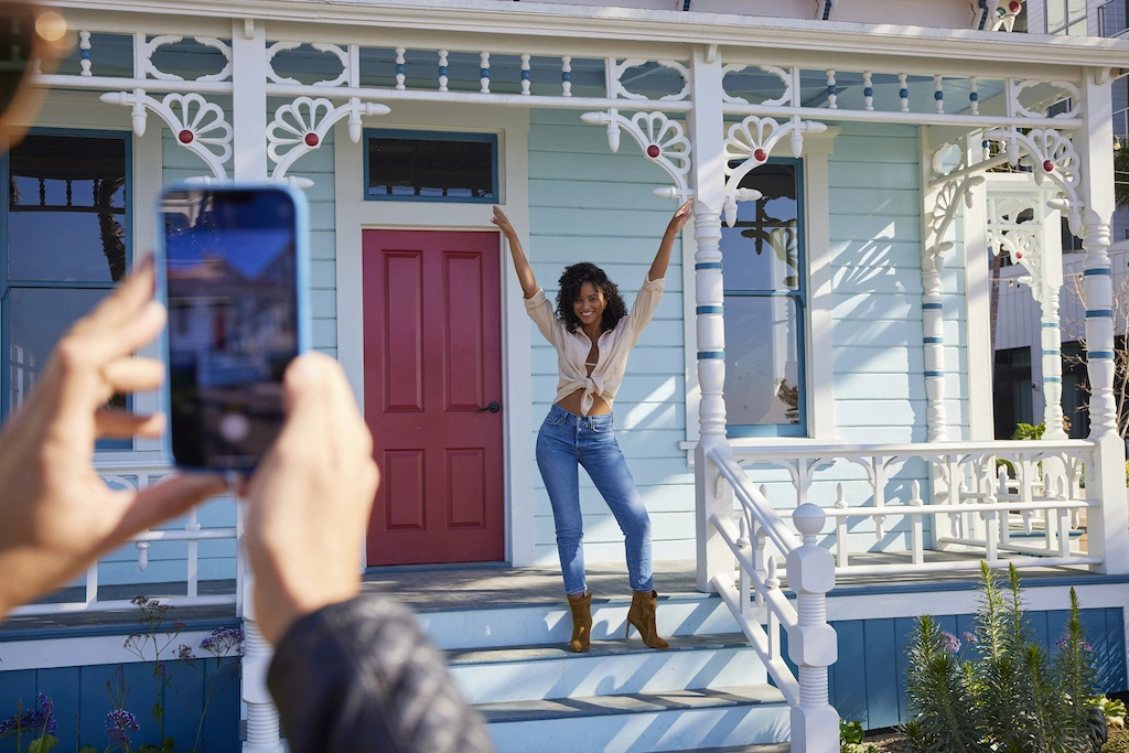 Woman posing on a colorful porch while someone takes her photo.