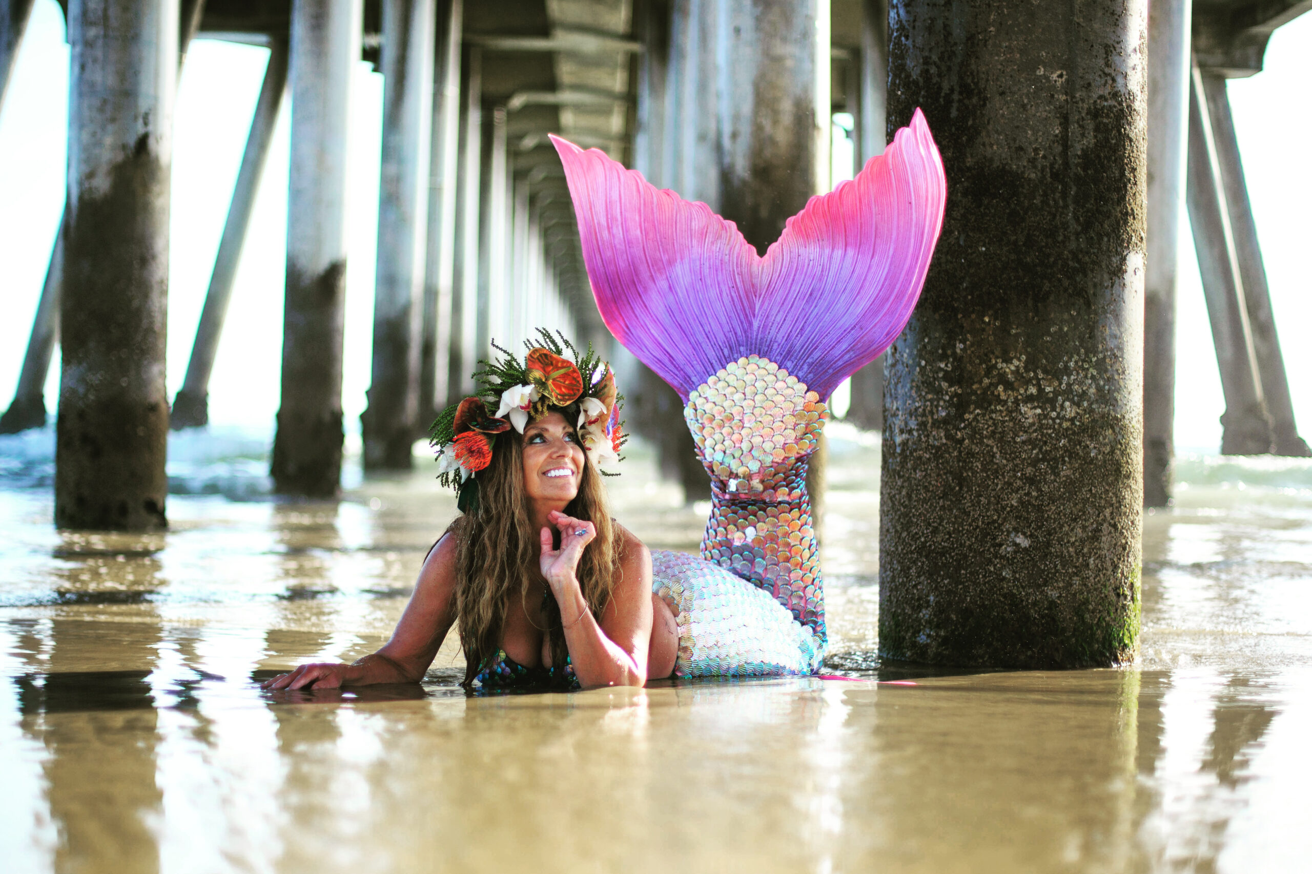 Mermaid laying under pier smiling